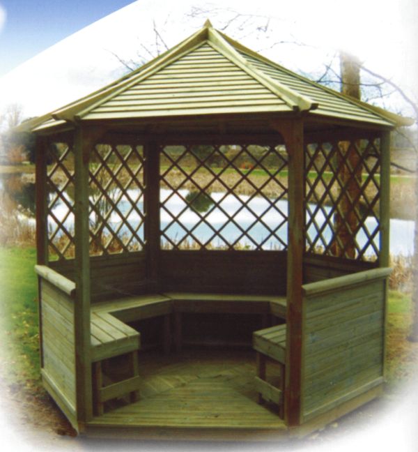 Sześcioboczna, drewniana altana z kratownicowymi ścianami i wbudowanymi ławkami, widok z zewnątrz na tle jeziora i drzew.